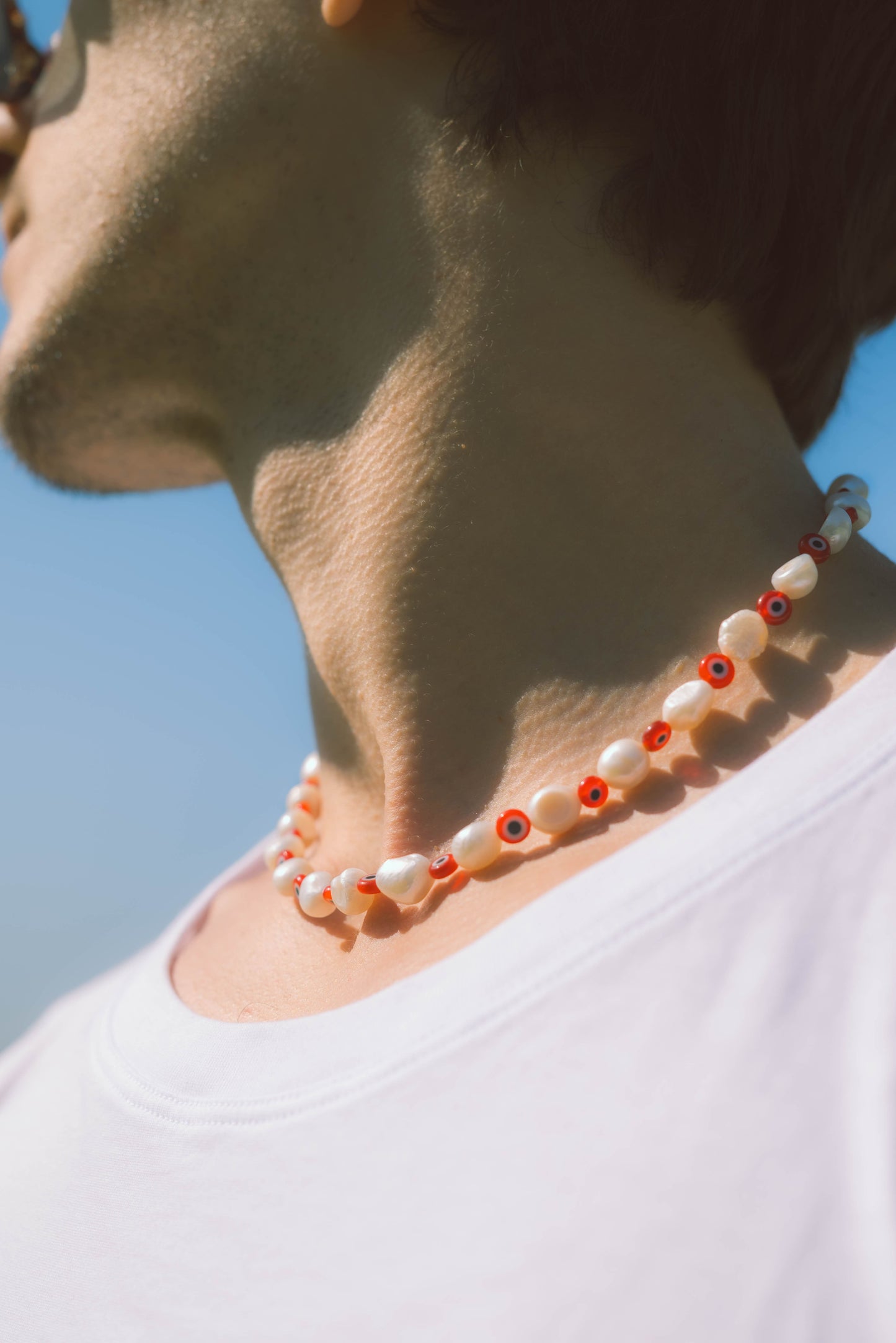 man wearing a red and white pearl necklace on a blue background